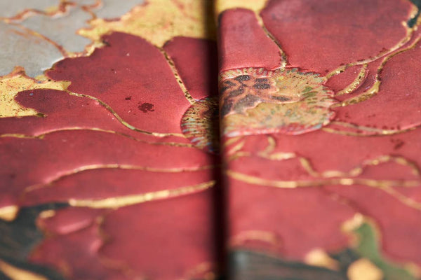 Close-up of a red and gold decorative surface, possibly a book or a piece of art.