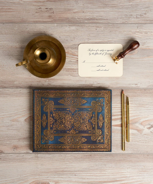 Decorative book, gold inkwell, quill pen, and letter on a wooden surface