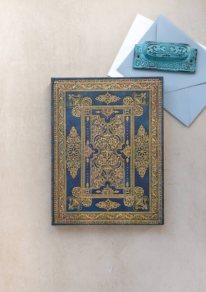 Decorative blue and gold book with matching card on a beige surface